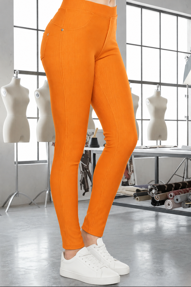 Magic Pant Tangerine detail in the signature atelier setting, with white sneakers.