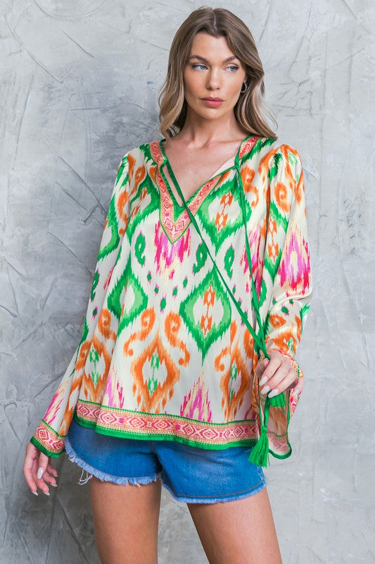 A Printed Woven Top Featuring Round Neckline with Front Tie and Tassel Detail, Long Bell Sleeve and Relaxed Body